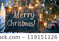 Festive chalkboard and Christmas decorations, lighting garland, candles, pine cone near Christmas tree. Text - Merry Christmas! Xmas card. 119151126