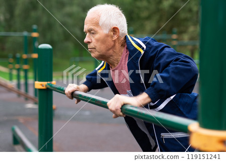 Mature man practice on the sports ground equipment in park Mature man practice on the sports ground equipment in park 119151241