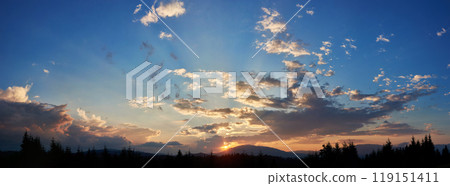 Serene evening sky with hues of blue and soft pink clouds as sun sets. Horizon glows gently, casting light over silhouetted pine trees and rolling hills, creating peaceful and expansive landscape. Serene evening sky with hues of blue and soft pink clouds as sun sets. Horizon glows gently, casting light over silhouetted pine trees and rolling hills, creating peaceful and expansive landscape. 119151411