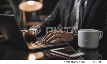 Busy executive working on laptop with smartphone and coffee nearby 119151943