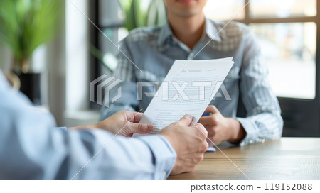 Job Interview in Modern Office, Candidate Meeting with Interviewer Holding Document at Desk in Professional Setting 119152088