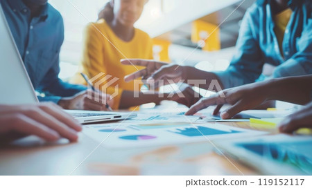 Diverse Team Collaborating Around Laptop Screen with Data Visualization in Modern Office Environment 119152117