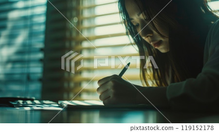 A woman is writing in a notebook 119152178