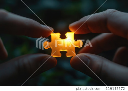 A person holding a jigsaw puzzle piece with a light shining on it. Concept of curiosity and the desire to solve the puzzle A person holding a jigsaw puzzle piece with a light shining on it. Concept of curiosity and the desire to solve the puzzle 119152372