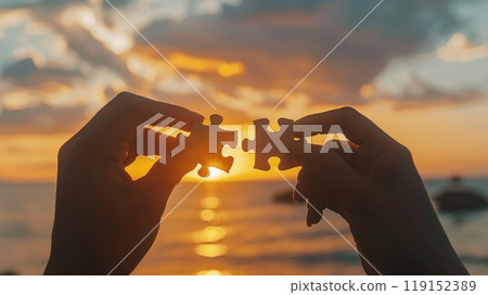 Two hands holding a puzzle piece with the sun in the background Two hands holding a puzzle piece with the sun in the background 119152389