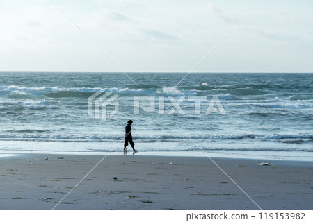 清晨在海灘散步的女人的剪影 清晨在海灘散步的女人的剪影 119153982