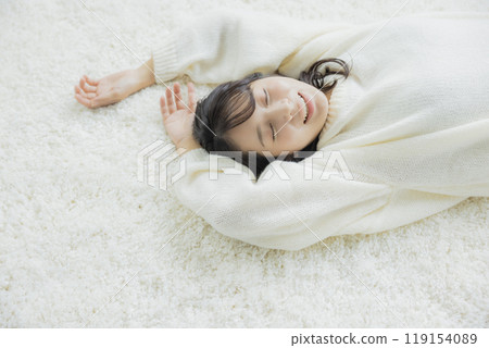 A woman lying down in a white knitted sweater A woman lying down in a white knitted sweater 119154089