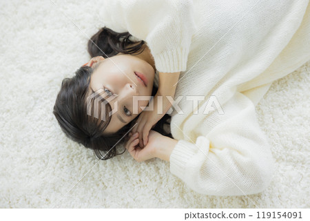 A woman lying down in a white knitted sweater 119154091
