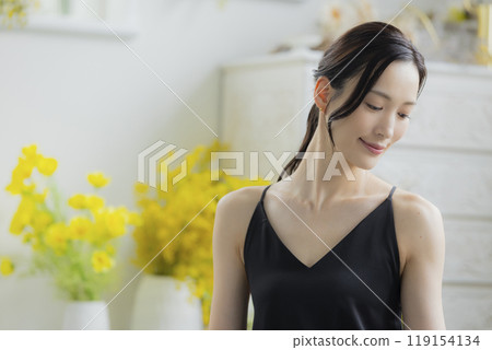 A woman in a black camisole dress standing by the window A woman in a black camisole dress standing by the window 119154134