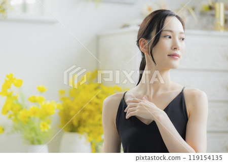 A woman in a black camisole dress standing by the window A woman in a black camisole dress standing by the window 119154135