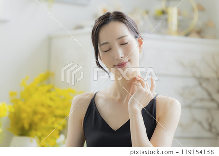 A woman in a black camisole dress standing by the window 119154138