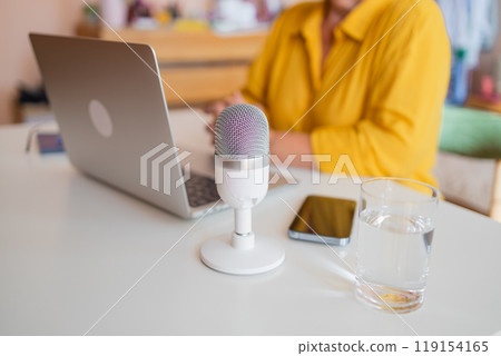 Female podcaster use smartphone and speaking with audience on microphone to recording video podcast. 119154165