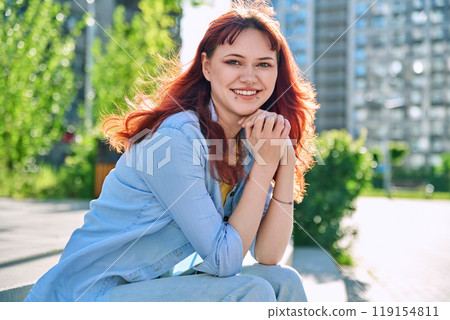 Young smiling red-haired hipster female with facial piercing looking at camera outdoor Young smiling red-haired hipster female with facial piercing looking at camera outdoor 119154811