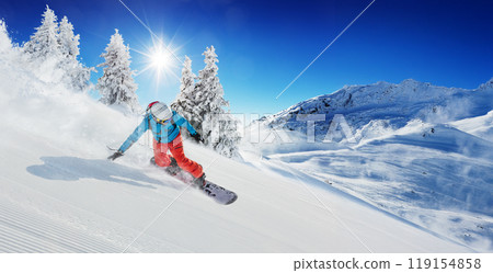 Snowboarder running downhill on sunny alpine slope 119154858