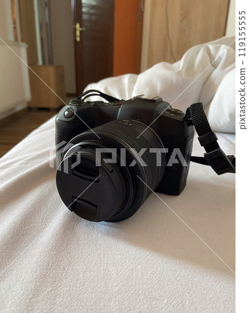 Digital camera rests on a white bed, ready for use, symbolizing creativity and exploration. Relaxed setting suggests a moment of pause before capturing new memories and experiences Digital camera rests on a white bed, ready for use, symbolizing creativity and exploration. Relaxed setting suggests a moment of pause before capturing new memories and experiences 119155555