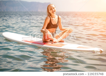 Woman sup sea. Sports girl on a surfboard in the sea on a sunny summer day. In a black bathing suit, he sits on a sapa in the sea. Rest on the sea. Woman sup sea. Sports girl on a surfboard in the sea on a sunny summer day. In a black bathing suit, he sits on a sapa in the sea. Rest on the sea. 119155748
