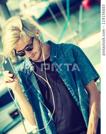 Blonde man in sunglasses listening to music 119156883