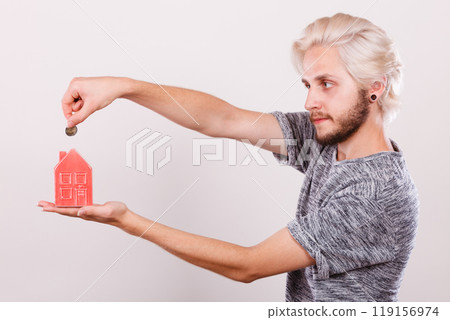 Man putting coin into house piggybank 119156974