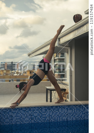 An Elegant and Graceful Diver Performing Acrobatic Moves at a Stunning Rooftop Pool 119157484