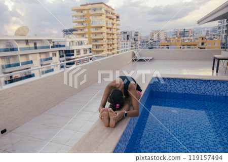 Engaging in a rejuvenating yoga practice by the tranquil poolside with a stunning urban view 119157494