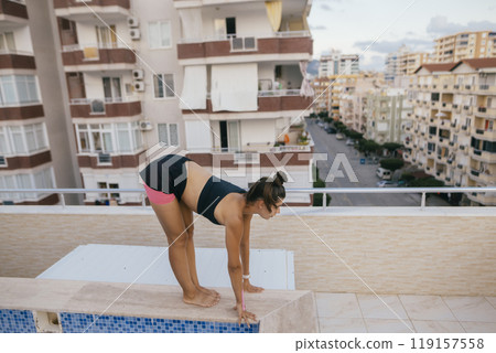 A fitness enthusiast does yoga on a scenic rooftop, embracing balance and tranquility A fitness enthusiast does yoga on a scenic rooftop, embracing balance and tranquility 119157558