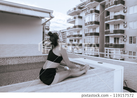A Serene and Relaxing Yoga Pose Performed on a Rooftop with a Lively Urban Background 119157572