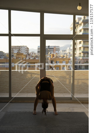 Engaging in a Yoga Session Inside a Modern Apartment Offering a Scenic and Beautiful View 119157577