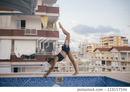 A Dynamic Acrobat Gracefully Performing a Handstand by the Relaxing Poolside Area 119157594