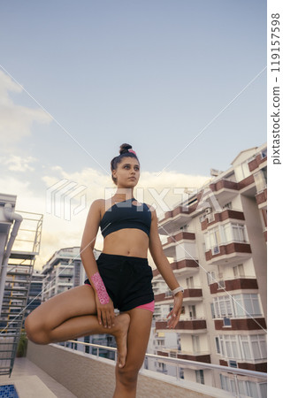 Engaging in a Yoga Practice on a Rooftop with a Stunning Urban Background at Sunset Engaging in a Yoga Practice on a Rooftop with a Stunning Urban Background at Sunset 119157598