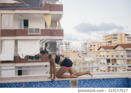 A Dedicated Fitness Enthusiast Engaging in a Challenging Workout Session on a Balcony 119157617