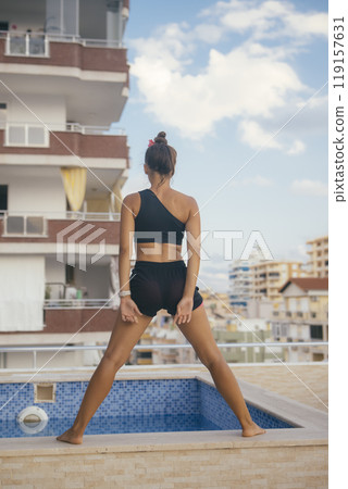 A Stylish and Confident Woman is Posing Gracefully by the Poolside in Trendy Summer Wear 119157631