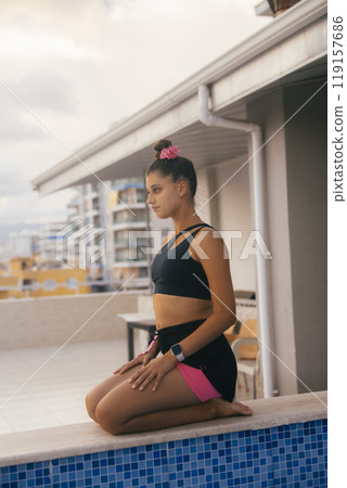 A young woman practicing yoga by the poolside in an urban apartment setting with calmness A young woman practicing yoga by the poolside in an urban apartment setting with calmness 119157686