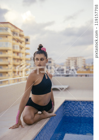 A Graceful and Young Dancer is Posing Elegantly by a Beautiful Rooftop Pool Area A Graceful and Young Dancer is Posing Elegantly by a Beautiful Rooftop Pool Area 119157708