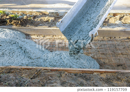 An cement mixing truck pours concrete on reinforced steel bars for construction of new sidewalk An cement mixing truck pours concrete on reinforced steel bars for construction of new sidewalk 119157709