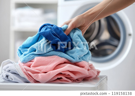A hand organizing freshly washed towels next to a washing machine A hand organizing freshly washed towels next to a washing machine 119158138