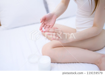 Young slender woman in underwear holding body cream in bed Skin care Body care 119159579
