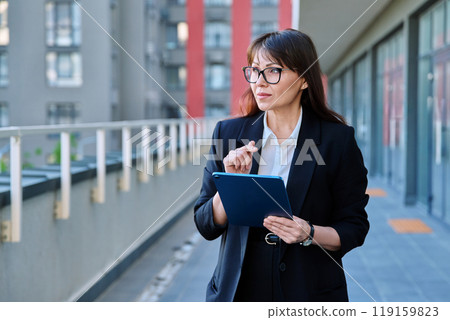 Mature woman manager agent using digital tablet for work, city background Mature woman manager agent using digital tablet for work, city background 119159823
