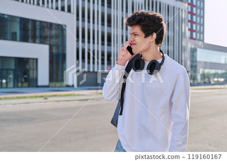 Young serious guy talking on mobile phone, modern city background, urban style Young serious guy talking on mobile phone, modern city background, urban style 119160167