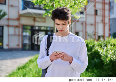 Handsome young male with backpack using smartphone, outdoor Handsome young male with backpack using smartphone, outdoor 119160168