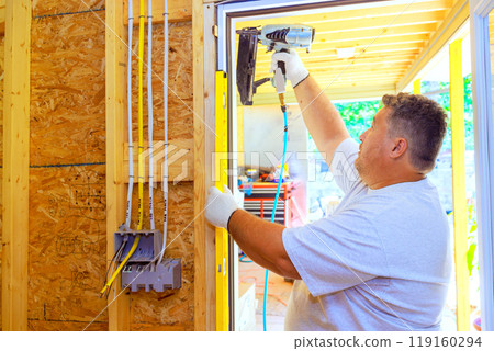 An experienced carpenter installs front door of new residence 119160294