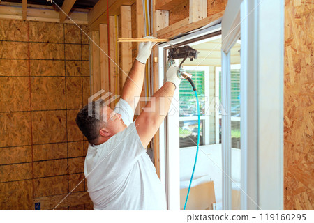 Installing front door of new home by professional carpenter 119160295