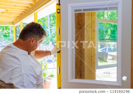 Front door of new home is installed by professional carpenter 119160296