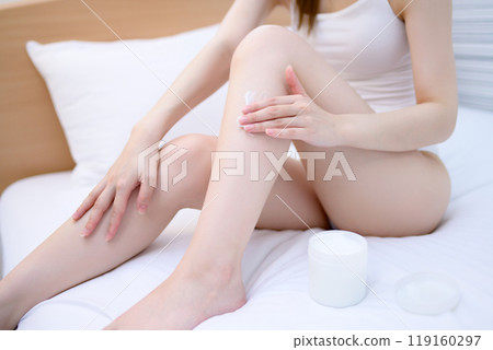 Young slender woman in underwear applying body cream to her legs in bed Skin care Body care Foot care Young slender woman in underwear applying body cream to her legs in bed Skin care Body care Foot care 119160297