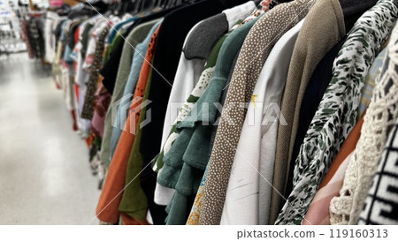 a rack filled with various clothing items in different colors and textures, hanging in a retail store 119160313