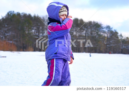 Frisky child girl walk on a frozen lake in a winter forest park Frisky child girl walk on a frozen lake in a winter forest park 119160317