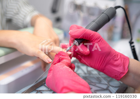 Manicure master uses a drill machine for a manicure at a beauty salon Manicure master uses a drill machine for a manicure at a beauty salon 119160330