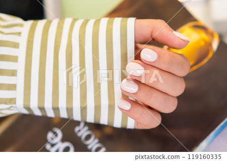 Fresh nude gel polish manicure showcased against a stylish backdrop in a contemporary salon  119160335