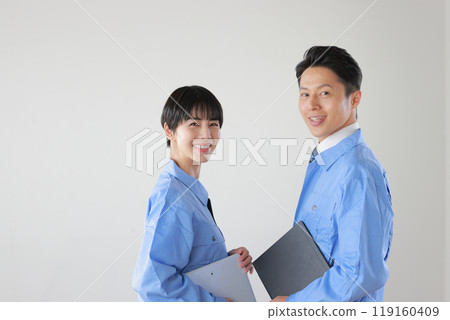 Staff wearing work clothes, male and female, holding a device and looking back_2 119160409