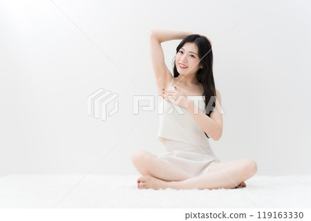 美麗的年輕女子盤腿坐著,擔心她的腋窩除毛 美麗的年輕女子盤腿坐著,擔心她的腋窩除毛 119163330