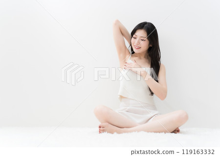 Beauty: A young woman sitting cross-legged and worrying about her armpits; Hair removal 119163332